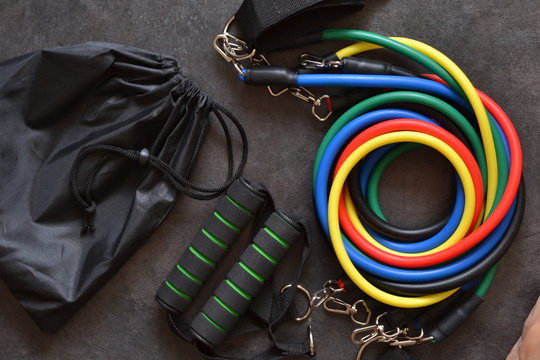Resistance bands in various colors with a black drawstring bag on a dark surface