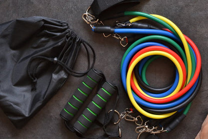 Resistance bands in various colors with a black drawstring bag on a dark surface
